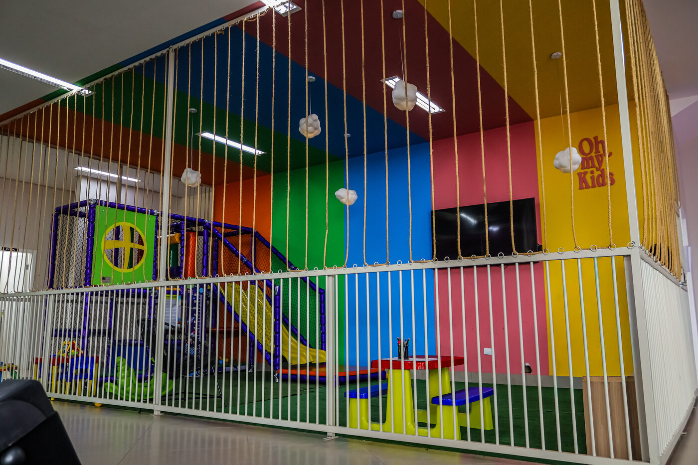 Entrada do espaço kids da Oh My Gym, com parede colorida e letreiro Oh my Kids