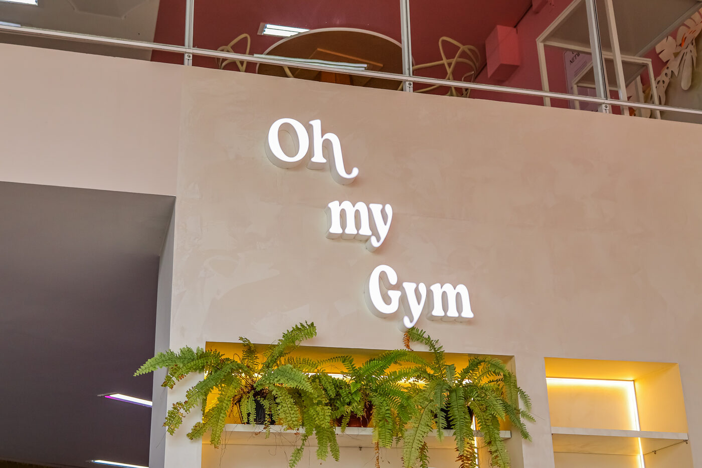Letreiro Oh my Gym em destaque no pé-direito duplo da recepção